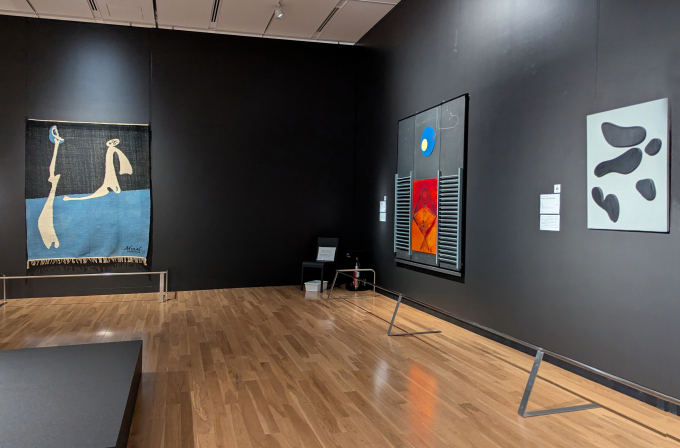 展示風景より、右からジャン（ハンス）・アルプ《灰色の上の黒い形態の星座》、マックス・エルンスト《偉大なる無知の人》、ジョアン・ミロ《無題『カイエ・ダール』９巻1-4号所収ステンシル》によるタペストリー