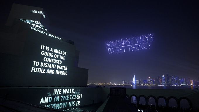 アート・バーゼル・カタールのプレビュー前夜のウェルカム・パーティでは、イスラム美術館の正面ファサードと中庭への映像投影、さらに700機以上のドローンによる夜空の演出が、ドーハの夜に輝いた。© 2026 by the Mahmoud Darwish Foundation.　© 2026 Jenny Holzer, member Artists Rights Society (ARS), NY Photo Courtesy by Art Basel