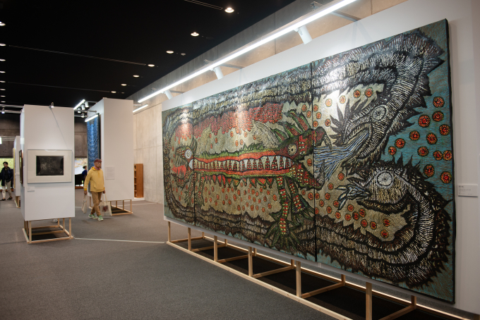 「九州派 イン ACK 『ローカル』からひもとく前衛美術史」Supported by JINTEX Corporation展示風景より。1958年に福岡市で生まれ、アスファルトの絵画を武器に、東京中心の美術制度に異議を問いかけた前衛集団「九州派」の活動を検証する展示内容。手前の大型絵画は、桜井孝身《ドラゴンシリーズI-IV》(1994)