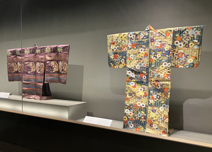 2領の装束は、大正期に新調された装束。手前の《白茶紺段竹山吹模様唐織》（大正10年〈1921〉 泉屋博古館東京）は、よく似た図様の唐織が池田侯爵家に伝わっており、本作はそれを写して作られたものと考えられている。