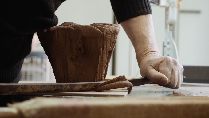 MOA美術館「特別展 十三代三輪休雪 茶の湯の造形」で上演された6分間の映像に収められた《エル キャピタン》の作陶風景より。刀で土塊を斬る成形の様子　映像より＝丸尾隆一
