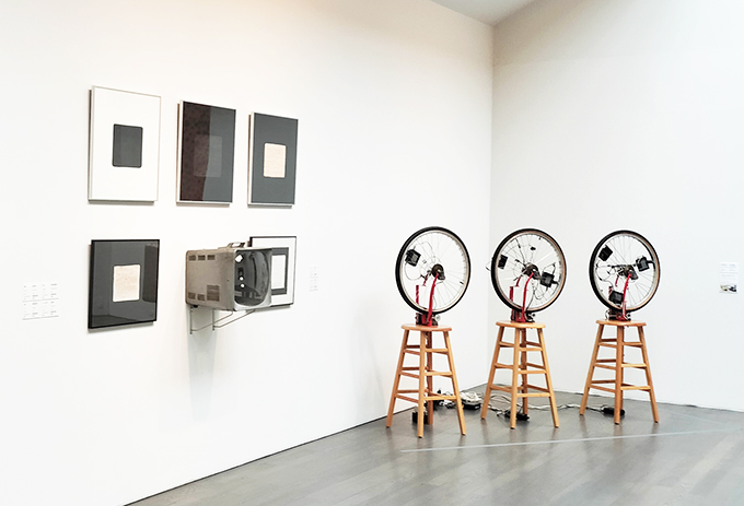 ギャラリーC展示風景
画像奥は久保田成子《デュシャンピアナ：自転車の車輪 1, 2, 3》、壁にはナム ジュン パイクの作品群が並ぶ。
