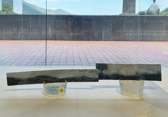 《立てかけ風景画》2023-24年　ティッシュペーパーの箱、ヨーグルトのカップ　作家蔵病室から眺めていた雲を見て、舟越は草原の向こう側に女性が横たわるイメージを思い浮かべ、ティッシュペーパーの箱に描いた。箱根の雄大な自然と広がる青空と、舟越が最期に見た幻想的な風景が重なる。